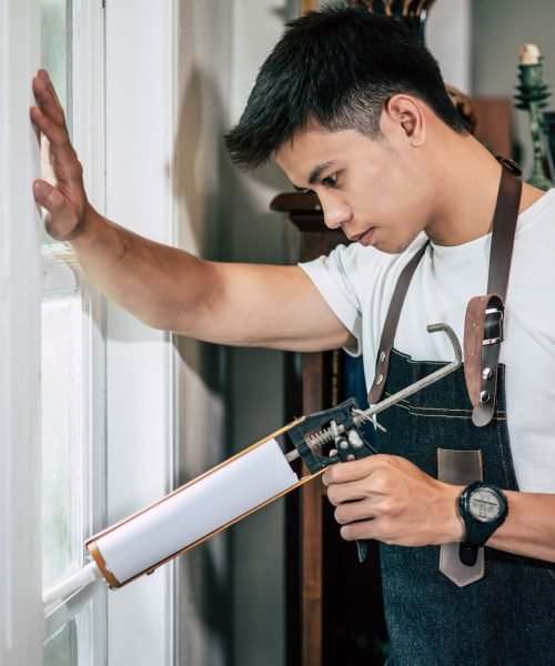 The carpenter holds the glue and attaches to the window. Selective focus.